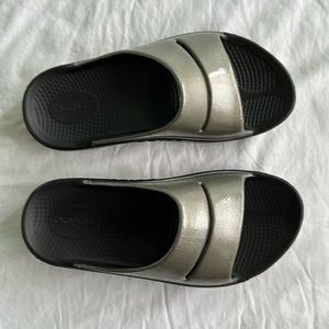 Oofos Women’s Ooahh Recovery Sport Slide. W7 Shiney goldish bronze color